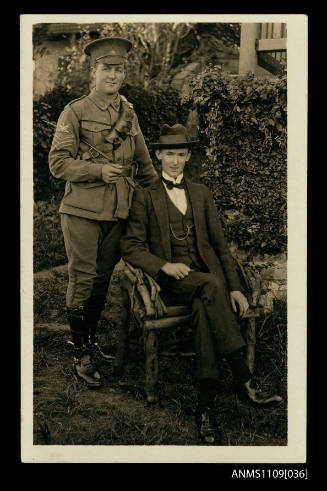 Photographic postcard of two men with one wearing military uniform