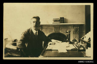 Photographic postcard of a man at his desk