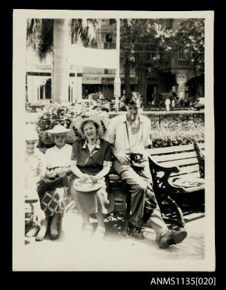 Group of women and a man on a park bench