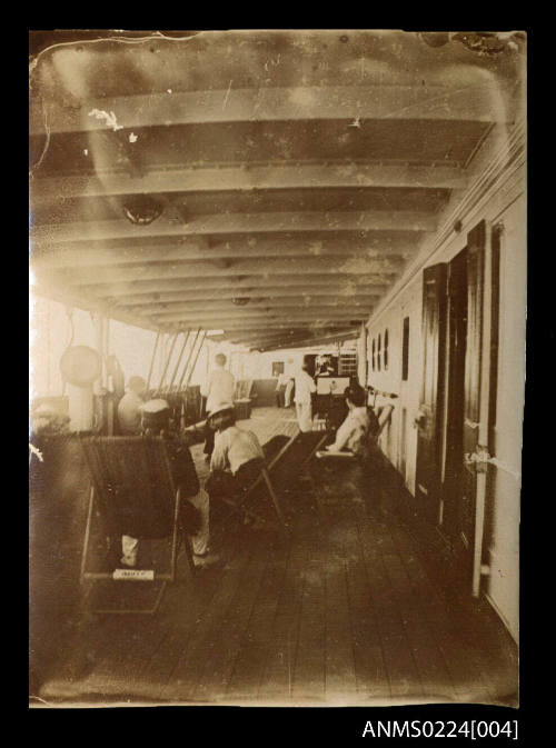 Man and two women seated on deck chairs