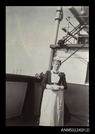 Photograph centre is a female in stewardess uniform, white apron, white frilly cap facing camera