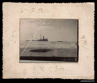 Photograph of starboard view of wrecked ship on shore partly submerged