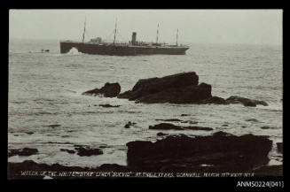 Port view of large passenger cargo ship aground, four masts, central single funnel between masts two and three