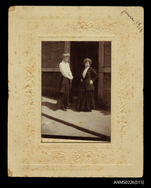 Two women standing at doorway of substantial stone building