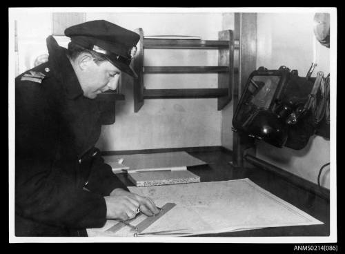 Unknown officer charting a voyage on chart in ship's bridge chartroom