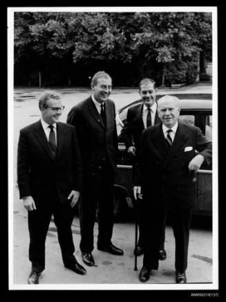 Four men posed in front of a car