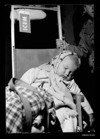 This young refugee, who was carried across the Yugoslav border from Hungary in his father's arms last spring, sleeps peacefully while his elders prepare for the long journey to Australia