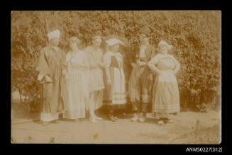 Six people in garden scene wearing costumes