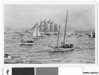 ESMERALDA, a four-masted barquentine of the Chilean Navy, arriving in Sydney Harbour escorted by many small craft. The Chilean ship is lowering its mizzen and jigger mast’s stay sails.