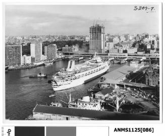 P&O liner CANBERRA entering her berth at Circular Quay assisted by a tugboat and with a three-masted barquentine in the background